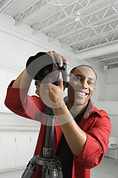 Young male with camera on tripod.