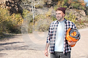 Young male camper with sleeping bag in wilderness.