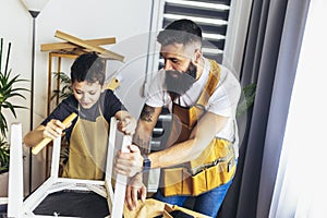 Young male carpenter and his son working in workshop