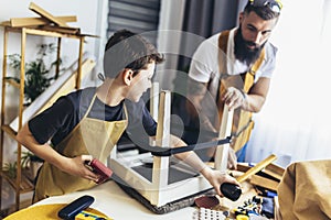 Young male carpenter and his son working in workshop