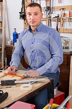 young male carpenter working wood plank at workshop