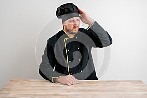 Young male chef in black uniform has headache