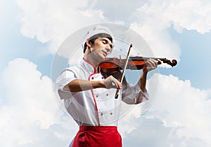 Young male chef playing violin