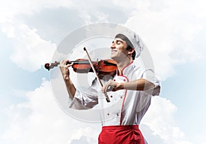 Young male chef playing violin