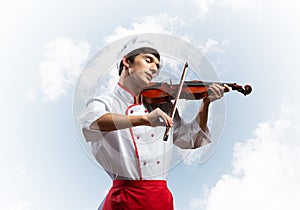 Young male chef playing violin