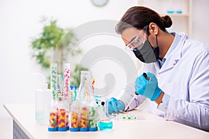 Young male chemist in drug synthesis concept