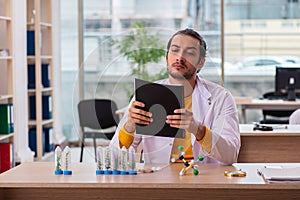 Young male chemist in drug synthesis concept