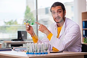 Young male chemist in drug synthesis concept