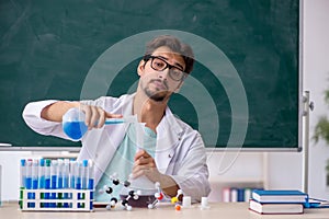 Young male chemist in front of blackboard