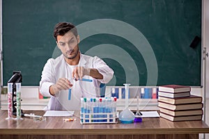 Young male chemist in front of green board