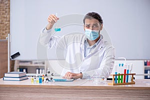 Young male chemist teacher sitting in the classroom