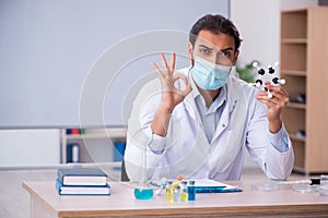 Young male chemist teacher sitting in the classroom