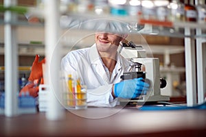 A young male chemistry student enjoying using a microscope in a laboratory. Science, chemistry, lab, people