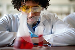 A young male chemistry student observes a chemical in a test tube in the laboratory. Science, chemistry, lab, people