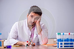 Young male chemistry teacher sitting in the classroom