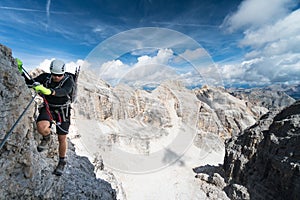 Young male climber on an exposed Via Ferrata in the Dolomites