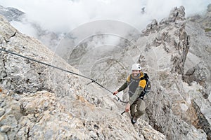 Young male climber on a steep and exposed rock face climbing a Via Ferratayoung handsome male climber on a steep and exposed rock