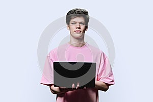 Young male college student using laptop, white background