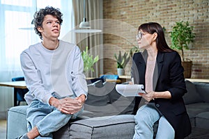 Young male communicates with female psychologist at therapy session in office