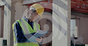Young male construction worker writing on clipboard