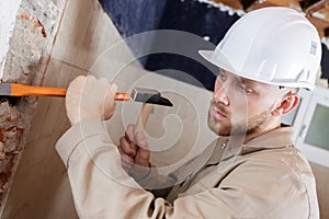 young male contractor using hammer and chisel