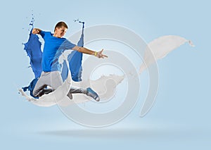 Young male dancer jumping with splash of paint