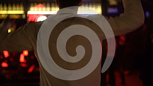 Young male dancing at disco bar, relaxing in night club on weekend, back view