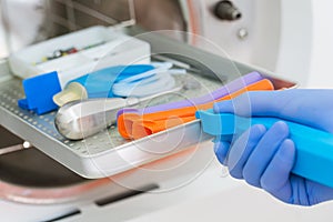 Young male dentist places medical autoclave for sterilising surgical and other instruments