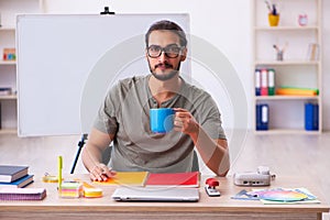 Young male designer drinking coffee in the office