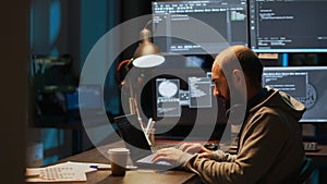 Young male developer typing server code on multiple screens