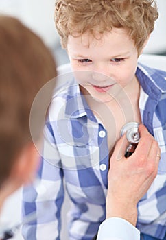 Young male doctor auscultating a little boy by stethoscope. Health care, insurance and help concept