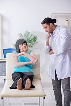 Young male doctor examining old female patient