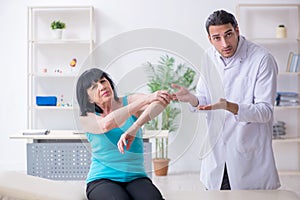 Young male doctor examining old female patient