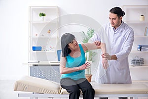 Young male doctor examining old female patient