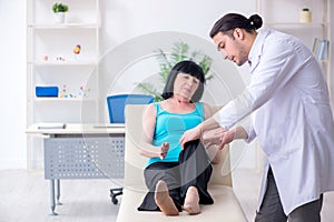 Young male doctor examining old female patient