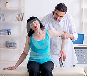 Young male doctor examining old female patient