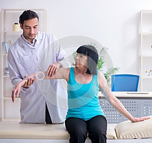 Young male doctor examining old female patient