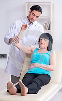 Young male doctor examining old female patient