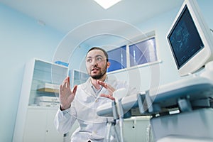 Young male doctor explaining ultrasound scan to pregnant woman in hospital