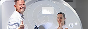 Young male doctor and female patient hold thumbs up in MRI room