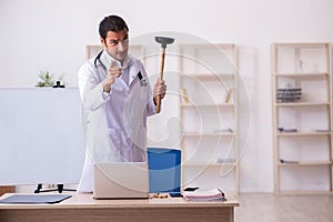 Young male doctor holding plunger in funny concept
