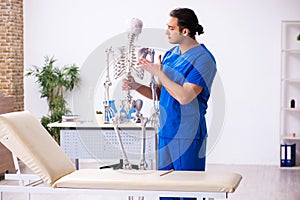 Young male doctor lecturer demonstrating skeleton