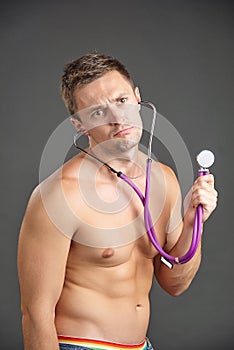 Young male doctor listening at stethoscope