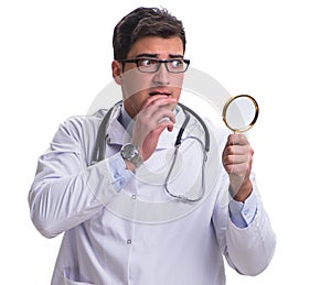 Young male doctor with a looking magnifying glass isolated on wh