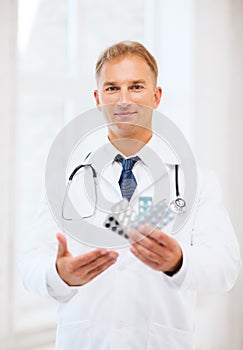 Young male doctor with packs of pills