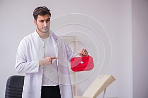 Young male doctor paramedic holding first aid bag