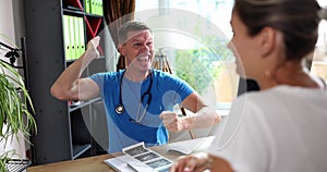 Young male doctor with a patient in clinic is annoyed and frustrated screaming in anger at female patient