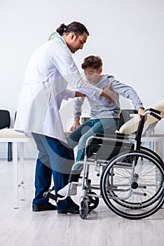 Young male doctor pediatrist and boy in wheel-chair