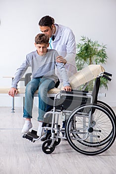 Young male doctor pediatrist and boy in wheel-chair