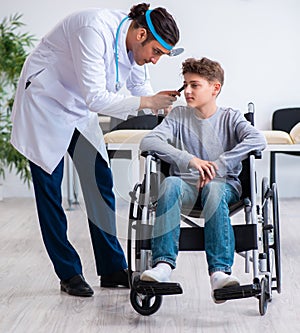 Young male doctor pediatrist and boy in wheel-chair